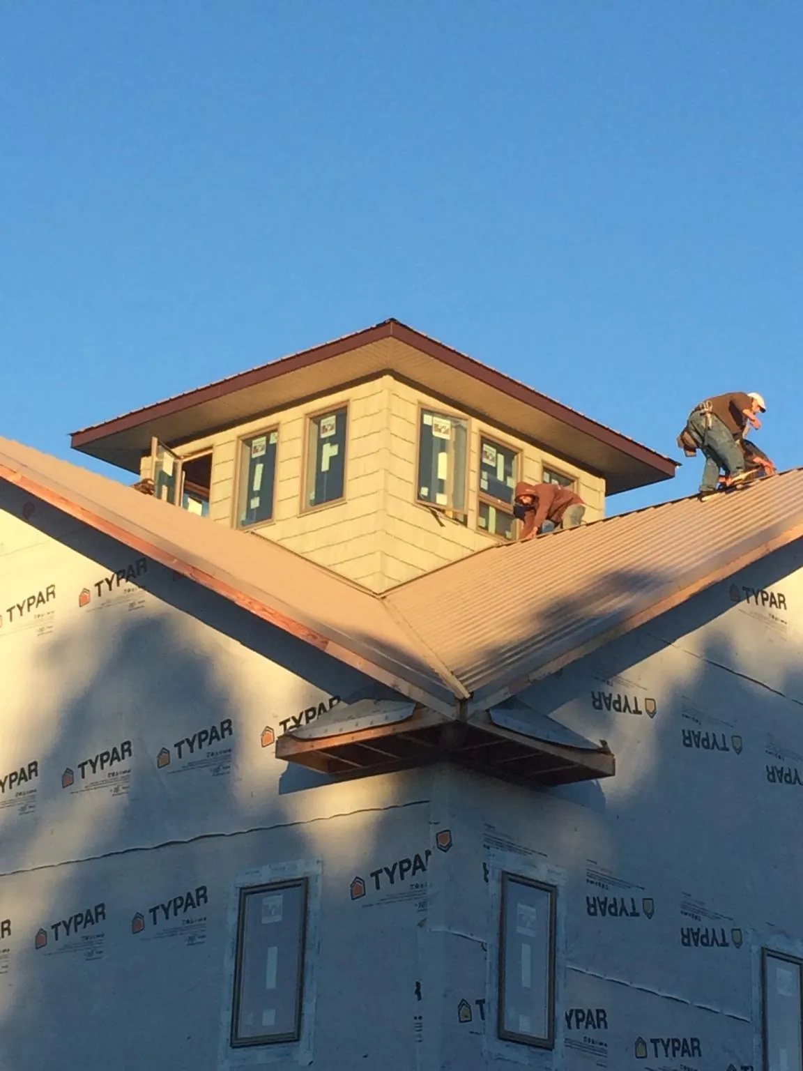 Roofers working around a rooftop cupola on a new metal roof at sunset — Roof Waterproofing in Belmont by Roofing Brothers